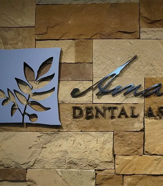 The Amarillo Dental Associates sign, cut from metal and set into the stone wall behind reception.